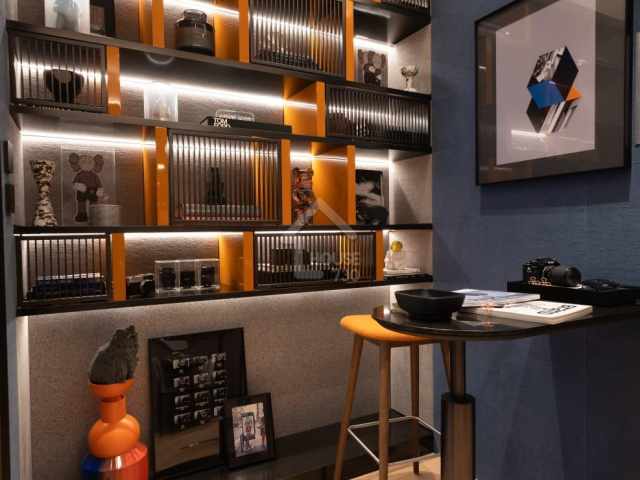 設計師特意把儲物室改造成迷你居家酒吧，黑橙配色組合展示櫃擺放潮流藝術收藏品，提升家居品味和格調。(資料圖片am730)